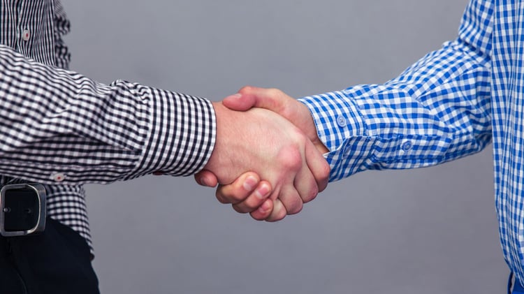 Zwei Männer geben sich die Hand, nachdem ihr Deal über HubSpot Funnel zustande gekommen ist.